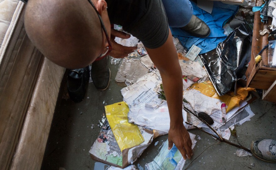 Lopez picks up wet electric bills inside of his home. Facing this powerful hurricane, even homes built according to code would not necessarily have been guaranteed to survive.