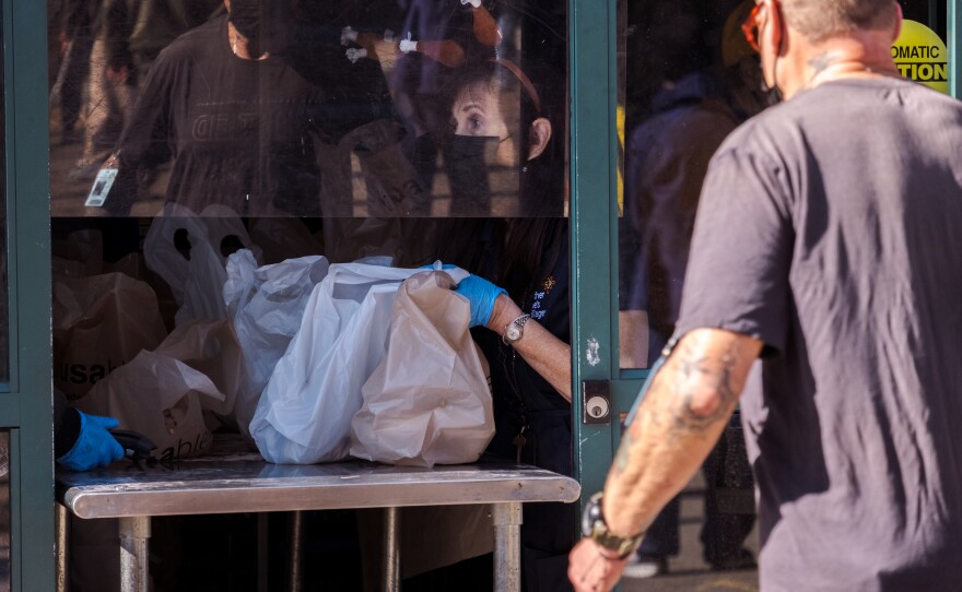 Volunteers hand people to-go Thanksgiving meals through a window at Father Joes in downtown San Diego, November 24, 2021.