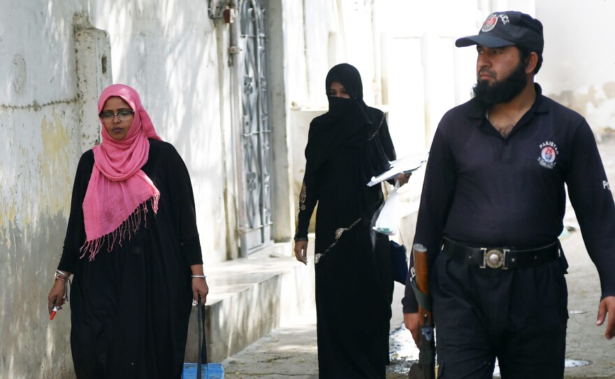 A Pakistani policeman guards a team of polio vaccinators during an immunization drive in Karachi on January 22. Officials have stepped up protection in the wake of the January 18 attack.