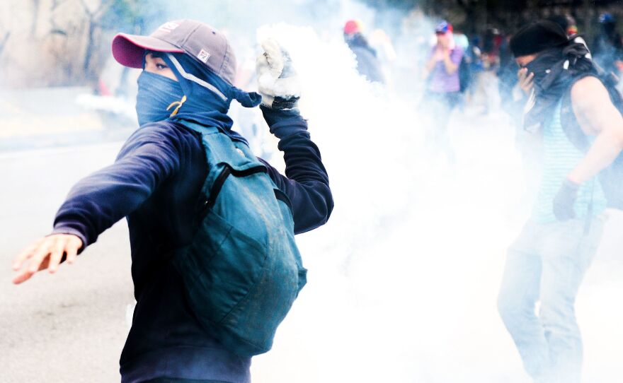 Opposition activists clash with riot police during protests Thursday. By the end of the day, a man had died of his gunshot wounds, bringing the number of people killed in past two weeks of protests to five.