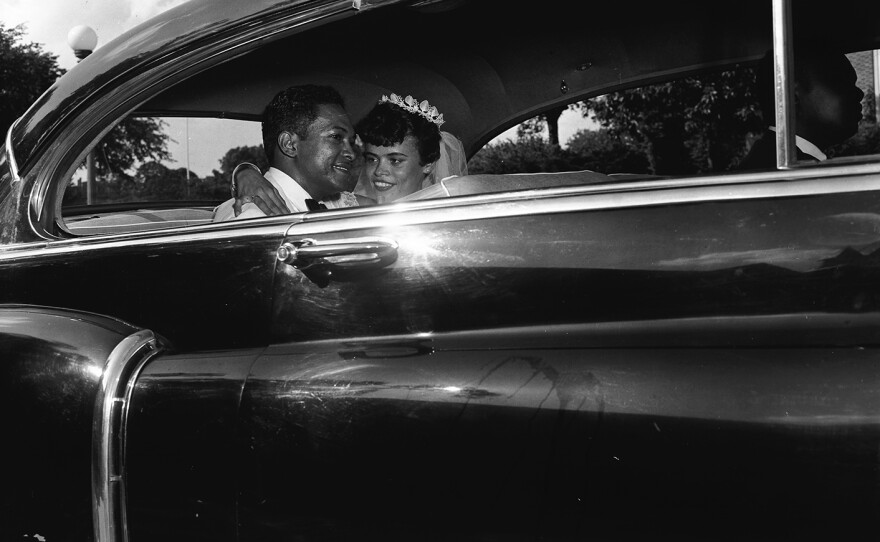 A bride and groom sit in a car.