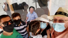 This handout photo provided by his family shows 93-year-old Wake Sharp, center behind plexiglass, visiting with three other generations of his family for Father's Day, Sunday, June 21, 2020, in Fairfield, California.