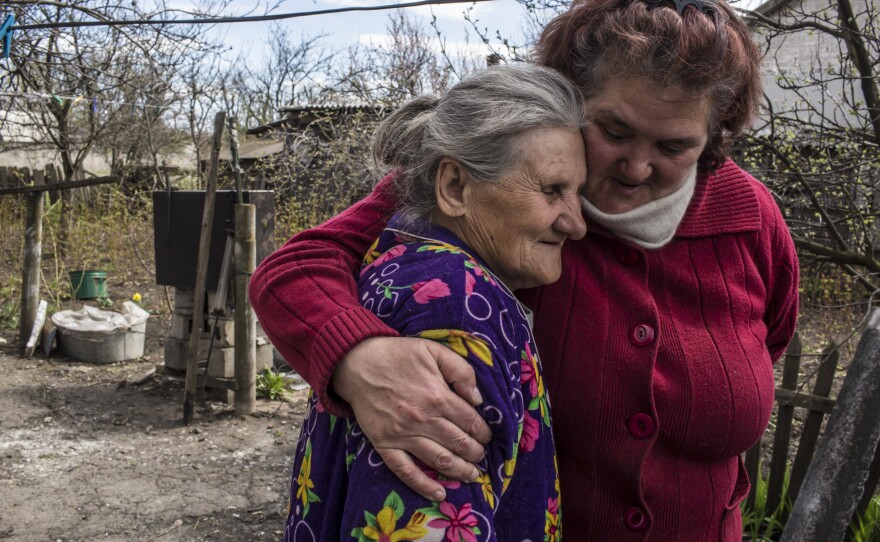 Raya Shaporova, 70, (left) a local resident who has not left despite the dangers of fighting all around, gets a hug from Vera Anoshina, 52, who lives nearby.