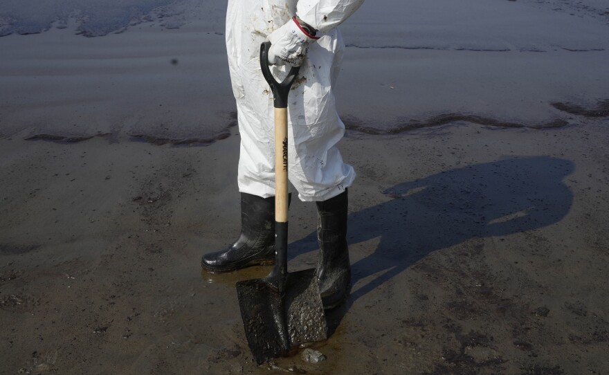 A worker pauses on Cavero beach during the cleaning away of oil on Tuesday.