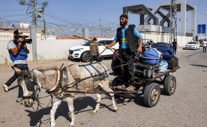 A journalist films a man driving a donkey-drawn cart carrying luggage outside the Rafah border crossing with Egypt in the southern Gaza Strip on Wednesday.