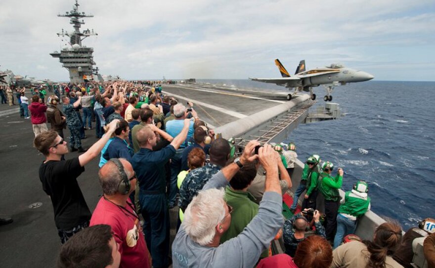 Sailors’ friends and family watch an F/A-18C Hornet, assigned to Strike Fighter Squadron (VFA) 25 launch from the flight deck of the Nimitz-class aircraft carrier USS Carl Vinson (CVN 70) during the ship's Tiger Cruise air show. Carl Vinson and Carrier Air Wing (CVW) 17 recently completed a deployment the U.S. 5th Fleet and U.S. 7th Fleet areas of responsibility, June 11, 2011.