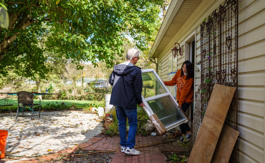 Zoe and her father Danny Turner carry a new window into their home, where they are storing materials to rebuild the property.