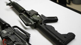 a semi-automatic rifle at right that has been fitted with a so-called bump stock device to make it fire faster sits on a table at the Washington State Patrol crime laboratory in Seattle, Jan. 11, 2018. 