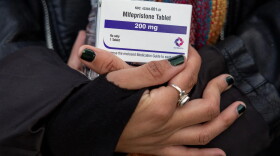 An abortion-rights activist holds a box of mifepristone pills as demonstrators from both anti-abortion and abortion-rights groups rally outside the Supreme Court in Washington on March 26, 2024.