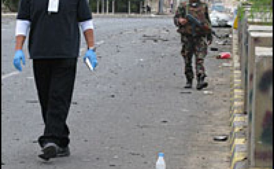 The morning after the assault, a U.S. investigator combs the street looking for evidence under the watchful eye of a Yemeni soldier.