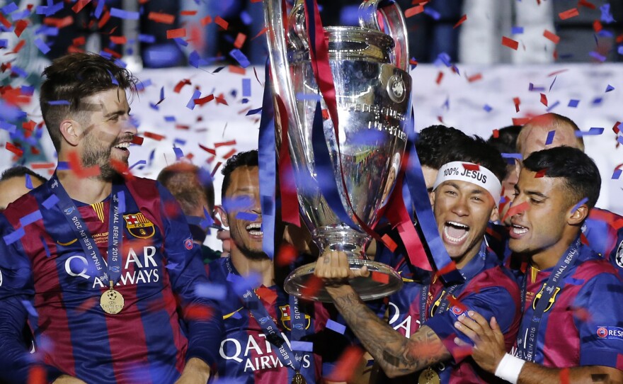 Barcelona's Gerard Pique (left) and Neymar (wearing headband) celebrate with the trophy after the Champions League final soccer match between Juventus Turin and FC Barcelona in June.