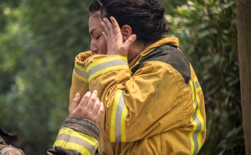 A firefighter mourns the loss of a colleague during a forest fire in the coastal resort of Llico, Chile.