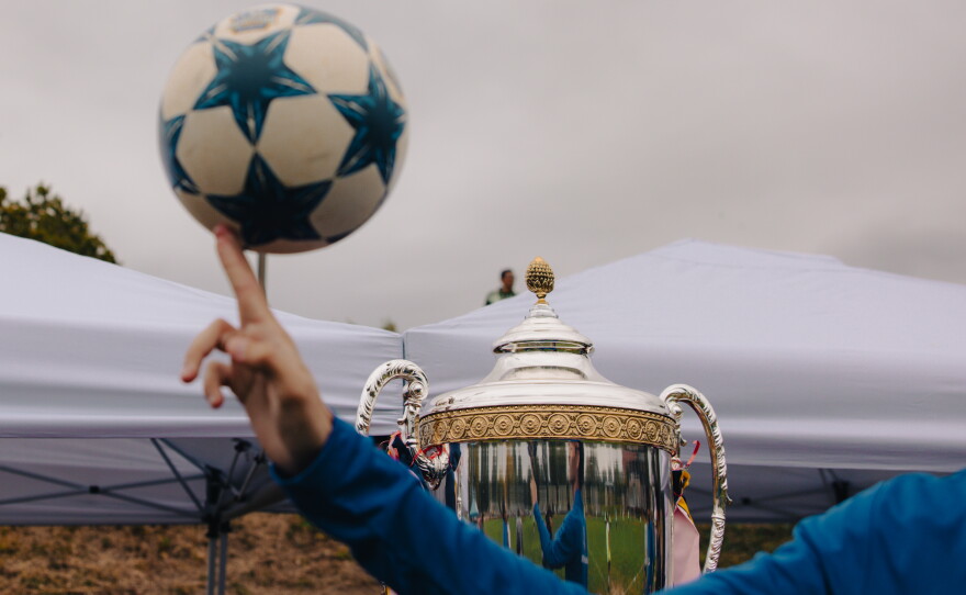 Shabin Subba, the head coach for ARU's Soccer for Success program, idly spins a soccer ball while watching the Kalu Singh Tamang Memorial Championship in Harrisburg, Pa., on Sept. 21, 2025.