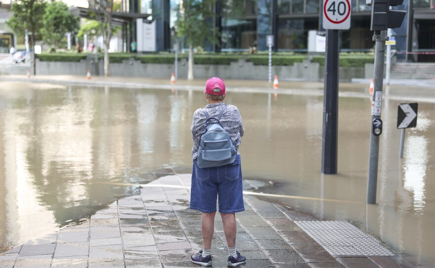 A local watches the floodwaters in Brisbane, Australia's central business district Monday.