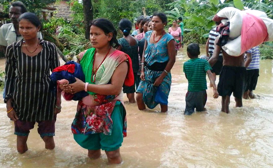 Families carry their belongings while moving to higher ground in the Bardia region of Nepal during the flooding on Aug. 15.