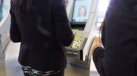 Two women are seen standing in front of an automated kiosk at the San Diego International Airport. 
