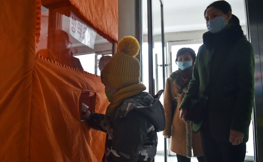 A child's temperature is checked and hands sanitized before entering the Pyongyang Children's Department Store as part of preventative measures against COVID.