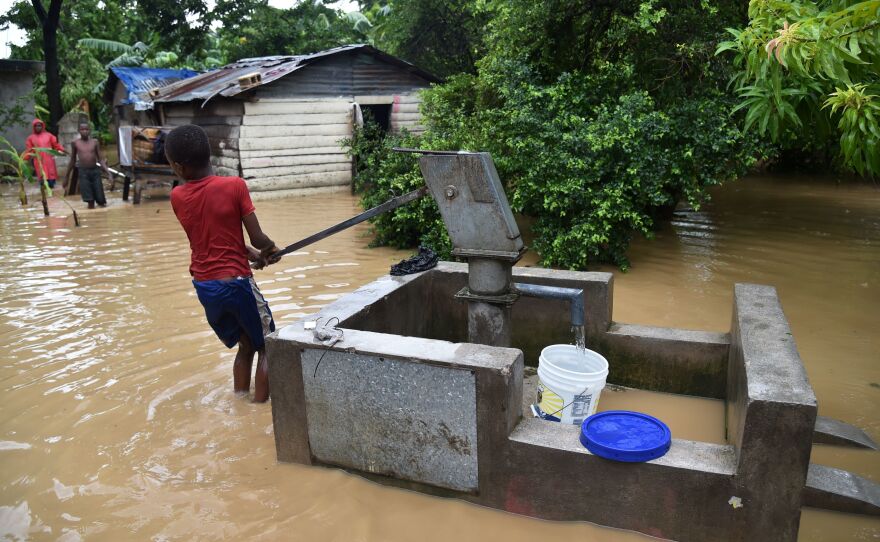 A boy pumps water close to his family's flooded home in Leogane on Wednesday.