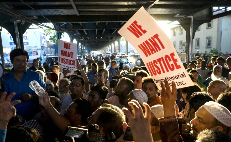 People gather for a demonstration Saturday in the Queens borough of New York, near a crime scene after the leader of a New York City mosque and an associate were fatally shot as they left afternoon prayers.