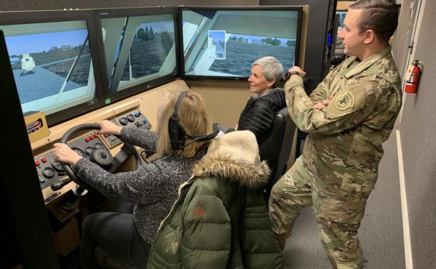 Teachers Kate Bridgman (left) and Lisa Jolstad of Cheyenne Mountain High School in Colorado, sit in a driving simulator at Fort Carson while Army Capt. Wes Barber looks on in this undated photo.