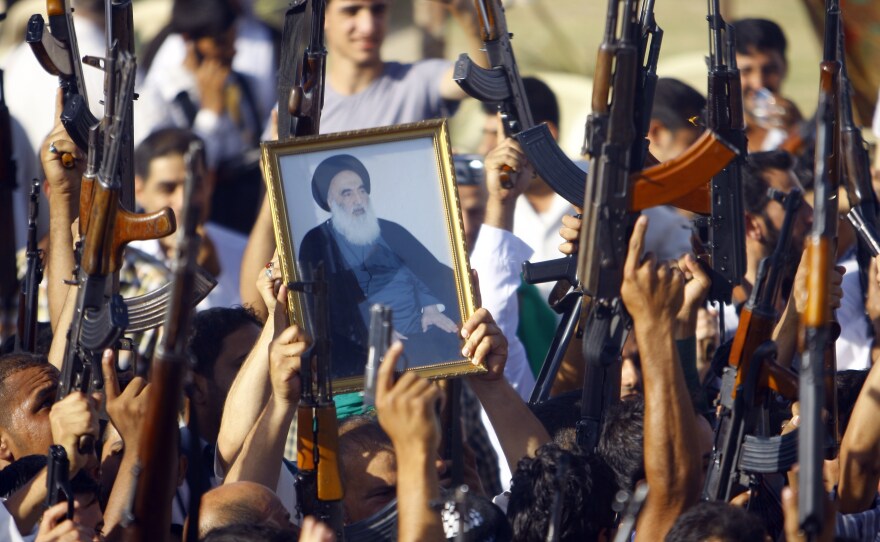 Iraqi Shiites in Najaf brandish their weapons and a poster of the Grand Ayatollah Ali al-Sistani, who broke with Iraqi tradition and called on Shiites to fight the current insurgency.