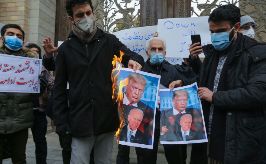 Iranian protesters burn images of President Trump and President-elect Joe Biden during a rally in front of the foreign ministry Saturday in Tehran. Iranian leaders have blamed Israel and its close ally, the U.S., for the assassination of a top Iranian nuclear scientist.