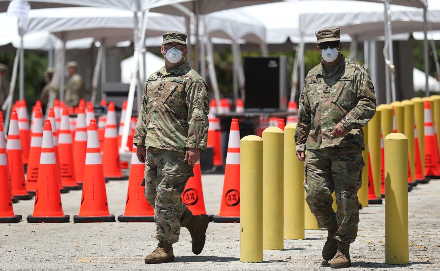 Members of the Florida National Guard are seen at a coronavirus testing site on April 27 in North Miami. Restrictions are easing, but officials worry people might now hesitate to evacuate during a hurricane.