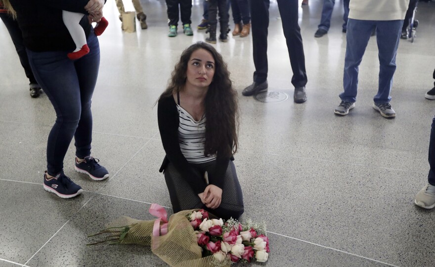 Reem Alrubaye, of Fremont, Calif., places flowers on the floor Jan. 30 as she waits for her mother, Mason Jadoaa, to return to San Francisco International Airport from a visit to Baghdad, Iraq. the rollout of President Trump's executive order barring citizens of seven countries from entering the United States was marked by poor communication within the government and with the public.
