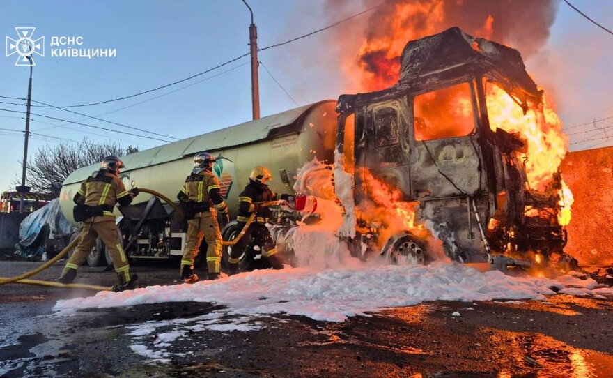 In this photo, provided by the Ukrainian Emergency Service, emergency services personnel work to extinguish a fire a vehicle following a Russian drone attack in Kyiv region, Ukraine, Tuesday, May 5, 2026.