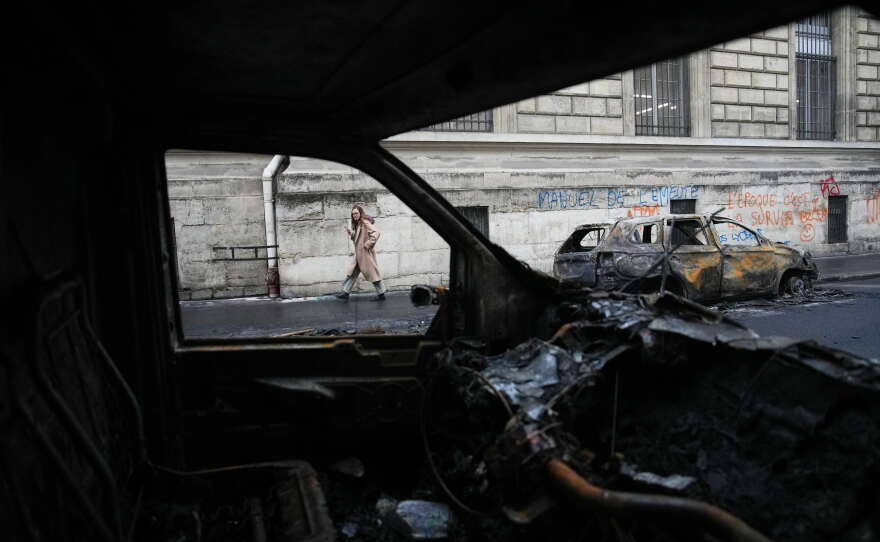 A woman walks past burned-out cars after a quiet night Monday under curfew, the first since weekend protests over the cost of living turned into rioting and looting across France, in Paris, Tuesday, Oct. 20, 2026.