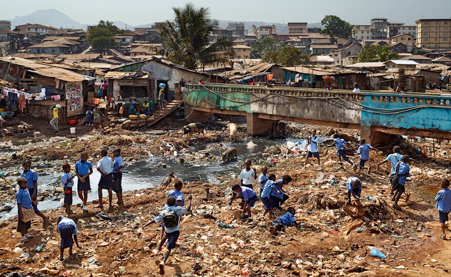 A contaminated river runs through the valley in Freetown, Sierra Leone, where there is neither sanitation nor garbage collection. Children from the nearby Kroo Bay primary school play amid the trash.