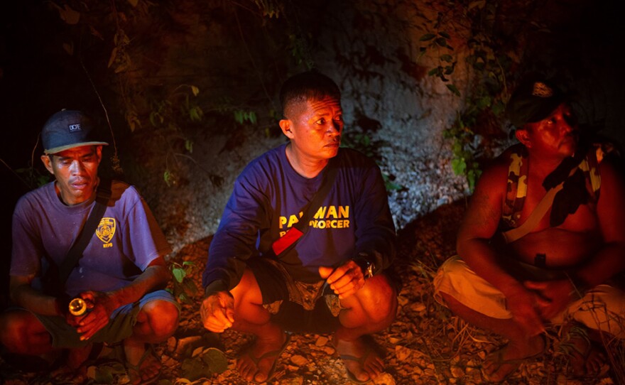 Tata Balladares and other para-enforcers sit around a campfire while on a chainsaw confiscation mission, Taytay, Palawan - April, 2018