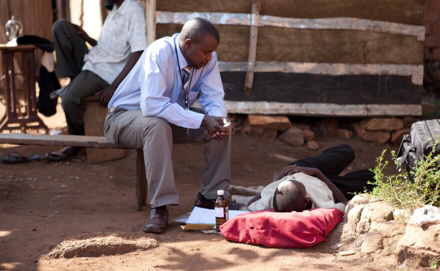 A palliative care physician visits an HIV-positive patient who lost her family to the AIDS epidemic. She's resting on a mat outside her home.