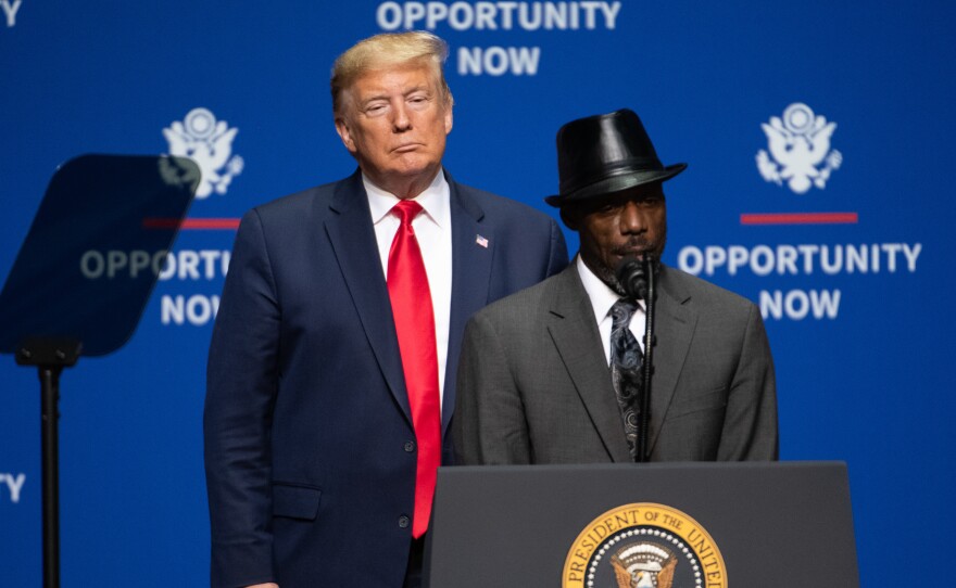 President Trump looks on as Tony Rankins, who works in a so-called Opportunity Zone, addresses a crowd during a speech Friday in Charlotte, N.C., aimed squarely at appealing to African American voters.