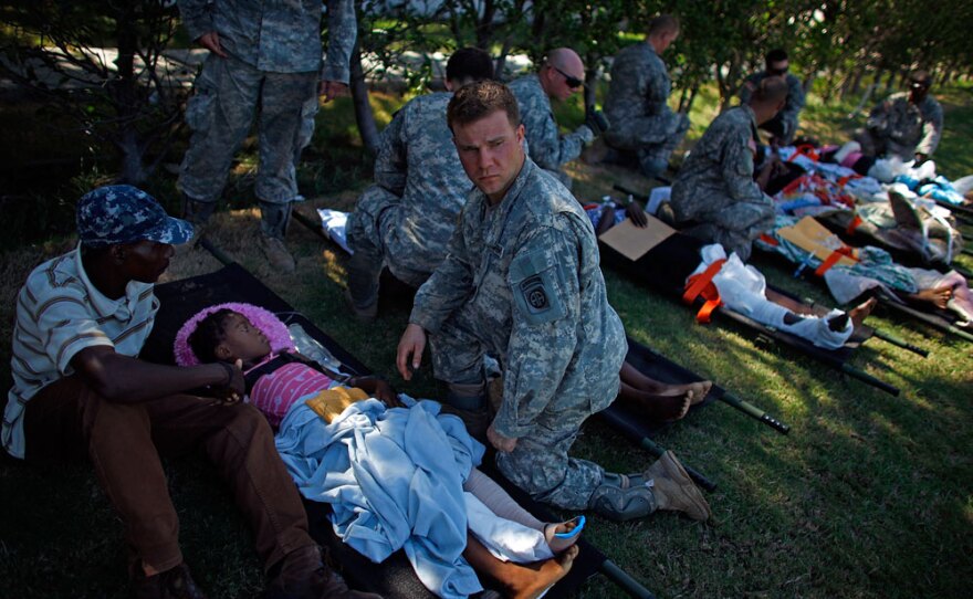 U.S. soldiers watch over patients in a staging area in front of the National Palace.