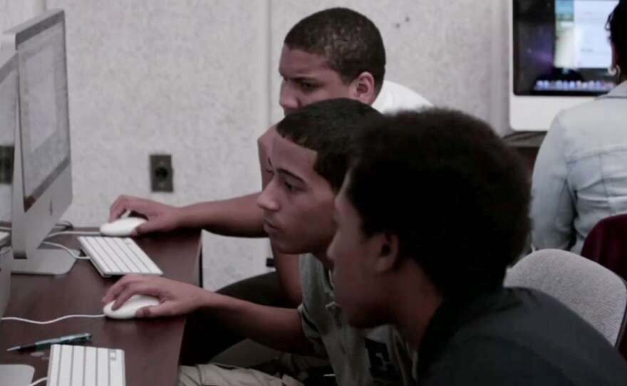Students working at computers as featured in "Is School Enough?"