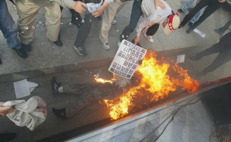 South Koreans help a protester who set himself on fire during a rally on May 7, 2004, in Seoul. A taxi driver attempted suicide during a rally demanding improvement of labor conditions and higher salaries for taxi drivers. The driver survived the attempt.