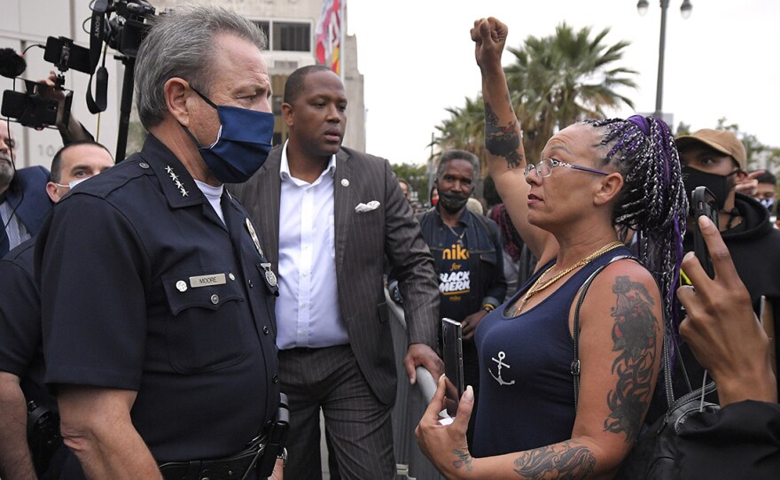 Los Angeles Police Department Chief Michel Moore speaks to a protester after a vigil with members of professional associations and the interfaith community at LAPD headquarters, Friday, June 5, 2020, in Los Angeles.