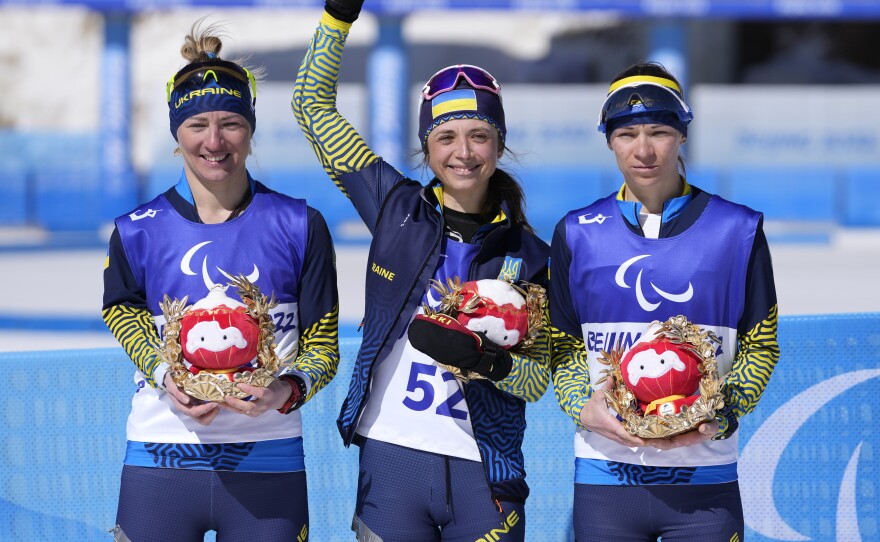 Gold medalist Iryna Bui (center) silver medalist Oleksandra Kononova (left) and bronze medalist Liudmyla Liashenko celebrate after the women's biathlon middle distance standing event at the 2022 Winter Paralympics on Tuesday.