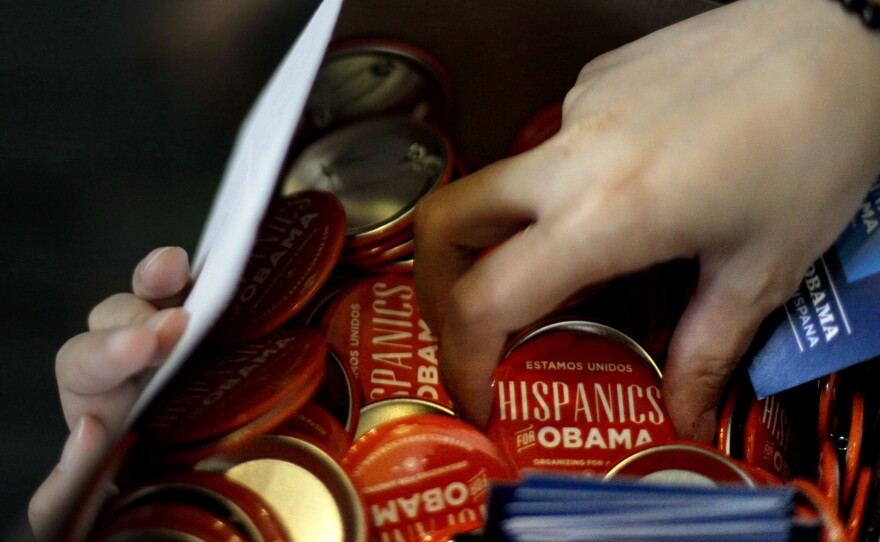 A volunteer hands out buttons before first lady Michelle Obama speaks at a Hispanic caucus on Sept. 5 in Charlotte, N.C.