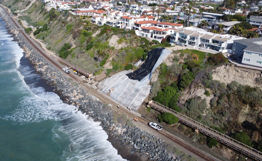 Crews placing plastic tarps ahead of a storm on the hillside in San Clemente, where a landslide shut down rail services between Orange County and San Diego, Jan.  31, 2024.