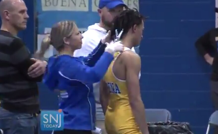 A video still shows Buena Regional High School wrestler Andrew Johnson getting his hair cut on Dec. 19, in Buena, N.J., after referee Alan Maloney told Johnson he would forfeit the match if he did not have his dreadlocks cut.