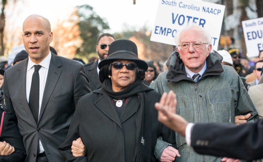 Sens. Cory Booker and Bernie Sanders, seen at a South Carolina NAACP march in January, are two of the 2020 Democratic presidential candidates pressed on the issue of reparations this week.