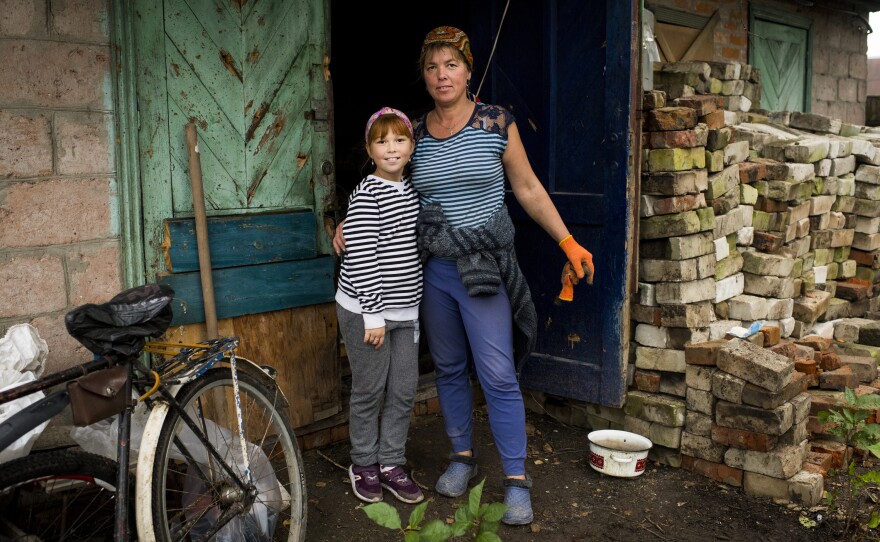 Tetiana Vereshchahina and her daughter Anastasiia, 9, stand next to a destroyed home owned by their family in Kolychivka.