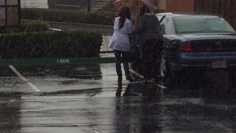 People struggle through the rain to get to their car in a parking lot in Kearny Mesa, Jan. 5, 2016.
