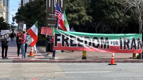 The San Diego Iranians Group stands around a large 'Freedom for Iran' sign holding flags and signs in honor of International Women's Day in Downtown San Diego on March 8, 2023.