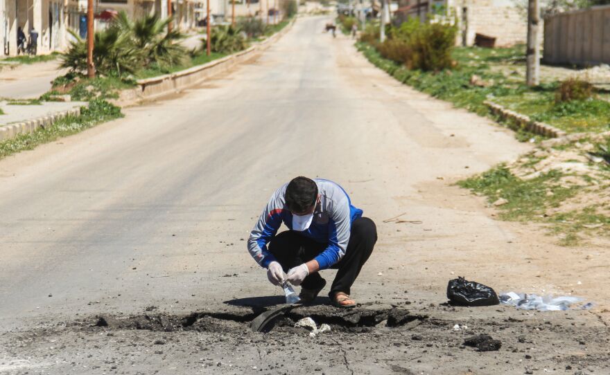 A man collects samples Wednesday from the site of a suspected toxic chemicals attack in Khan Shaykhun the day before.