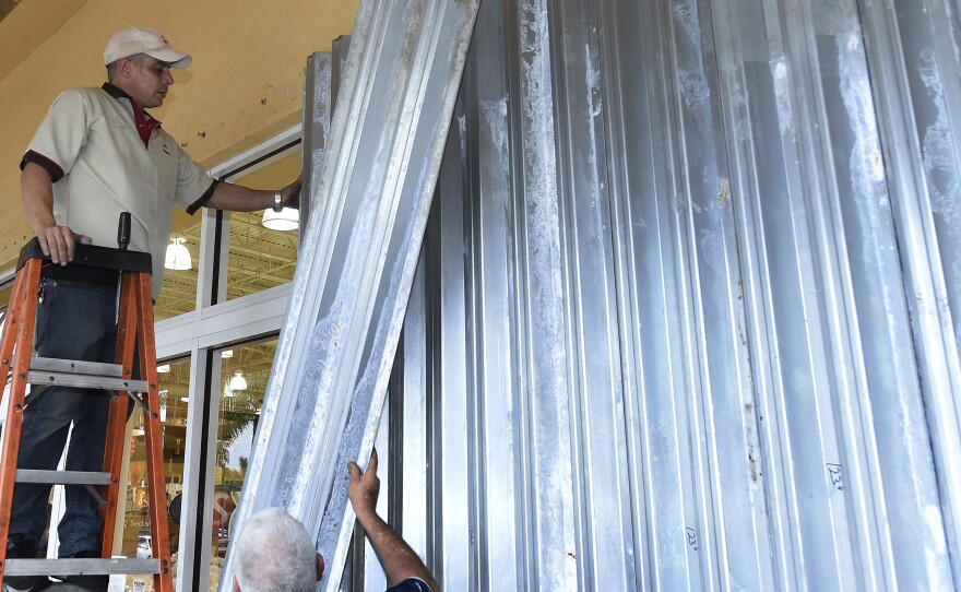 Workers put up shutters at a strip mall in preparation for Hurricane Matthew in Miami on Thursday. Some 3 million people on the Southeast coast faced an evacuation order.