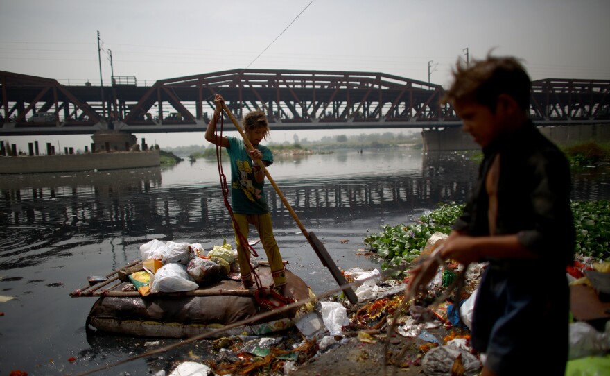 In the shadow of the British colonial Old Iron Bridge, children ply the Yamuna River in makeshift rafts and scour its banks in search of anything valuable to help their families eke out an existence.