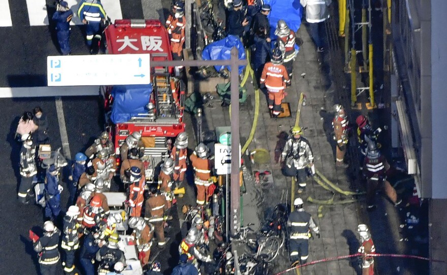 Policemen and firefighters gather near a building where a fire broke out in Osaka, western Japan on Friday. Dozens of people are feared dead, fire department officials said.